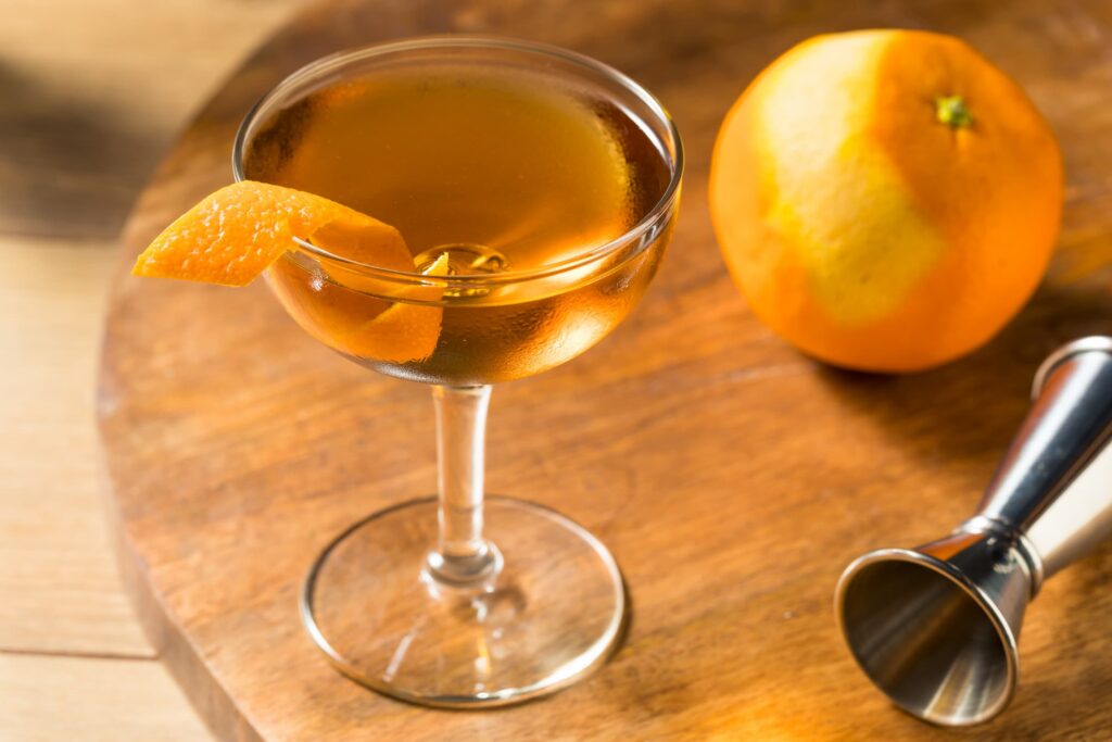Hanky Panky cocktail on a wooden table next to an orange.